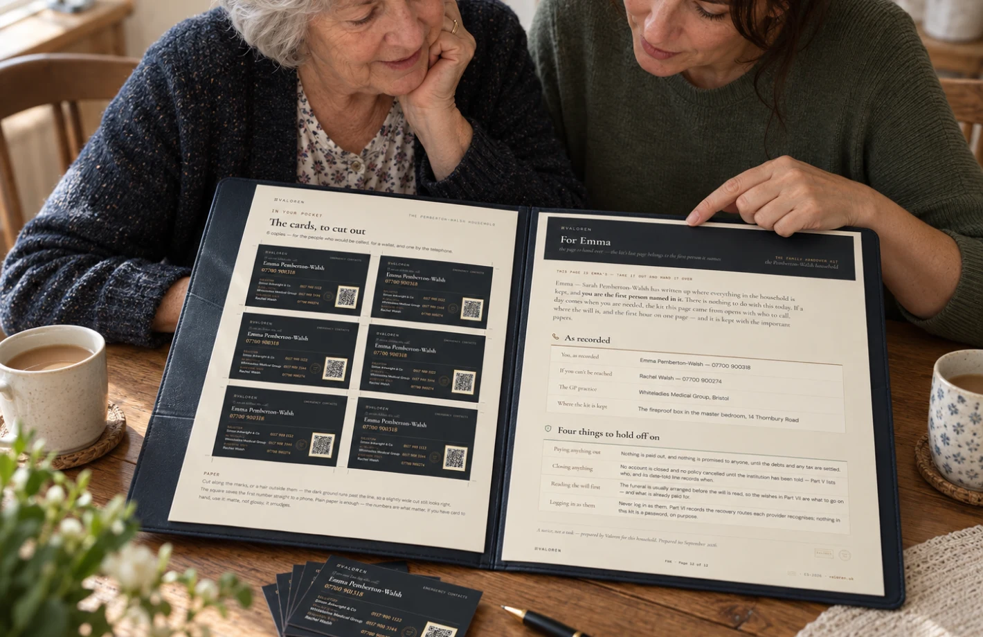 Two women at a kitchen table with the open kit between them: the older is pointing at the sheet of cut-out cards, the younger is reading the page addressed to her.